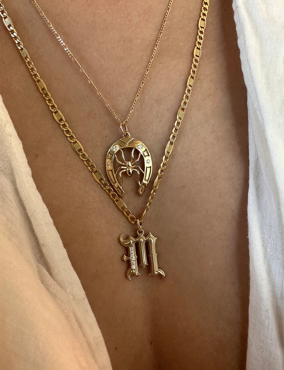 Gothic Initial charm in 14k gold with diamonds paired with a lucky spider horseshoe pendants by honey drip.