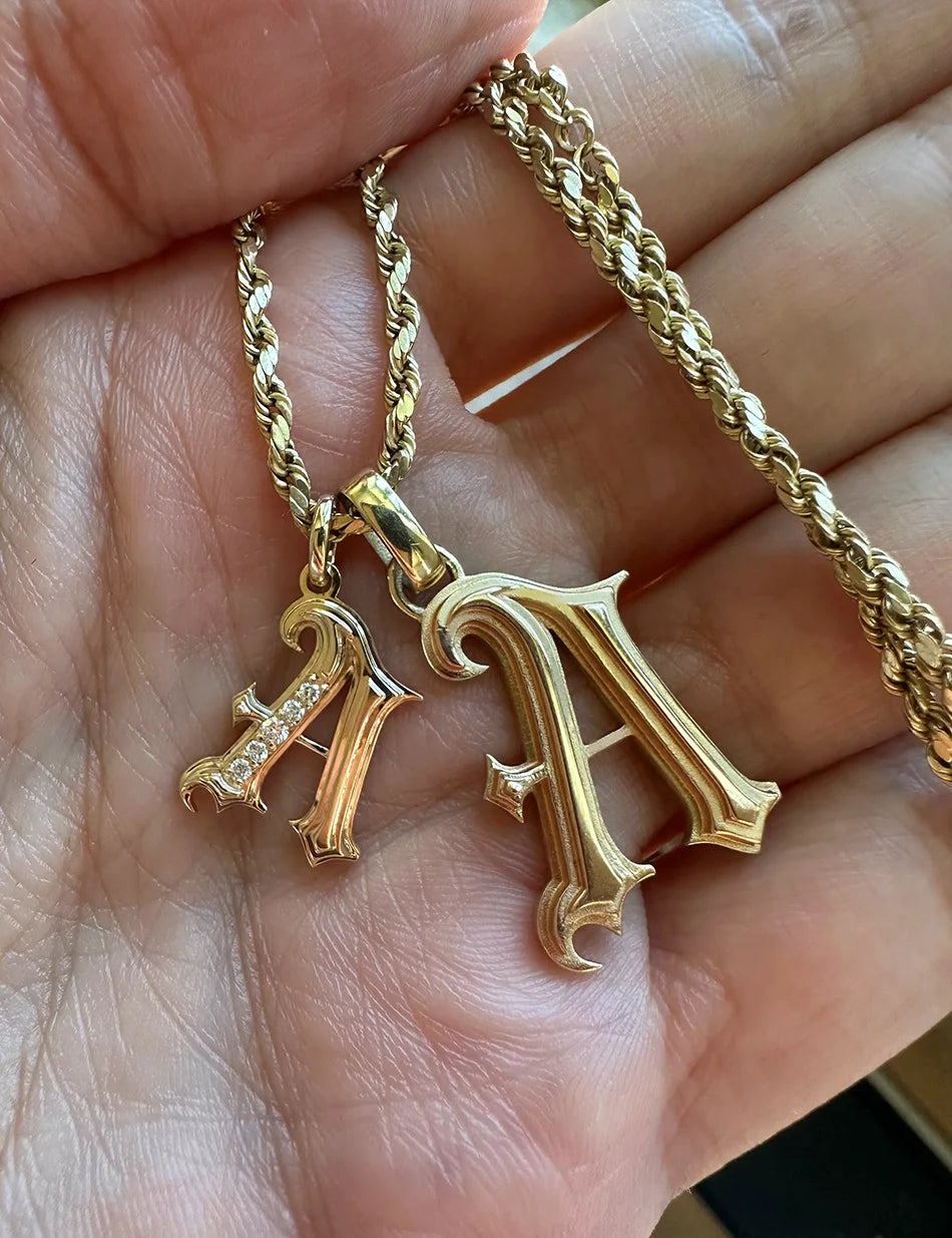 two sizes of gothic letter charm pendants in 14k gold with diamonds by honey drip jewelry