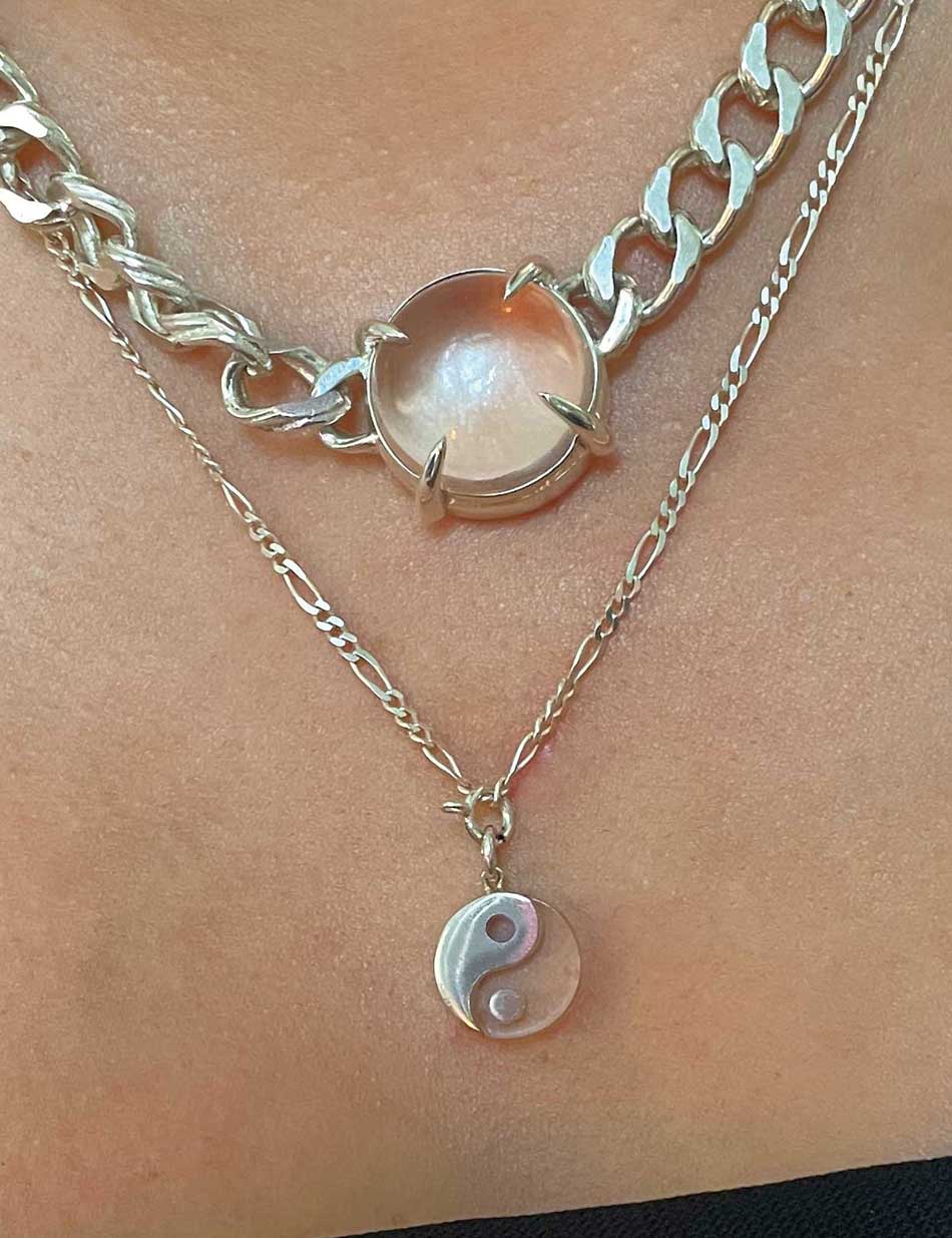 A close up of the Fortune Teller collar and the Balance Yin Yang pendant worn by a person, both in sterling silver and quartz crystal.